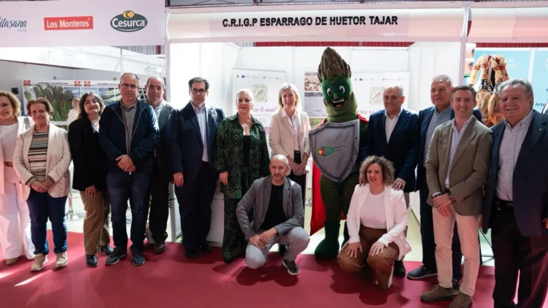 Grupo de autoridades, representantes del sector y la mascota con forma de espárrago posando en el stand de la IGP Espárrago de Huétor Tájar durante la III Feria Gastronómica.